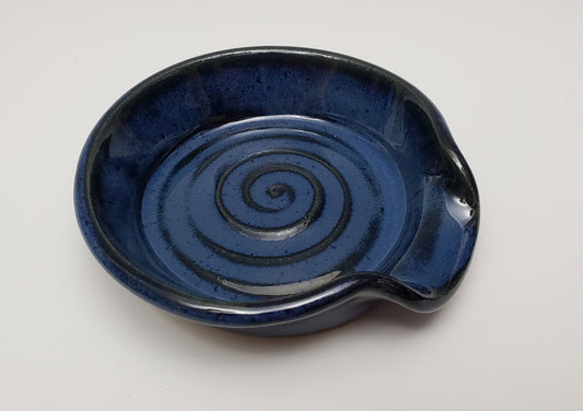 Blue stoneware spoon rest with spiral design on a white background