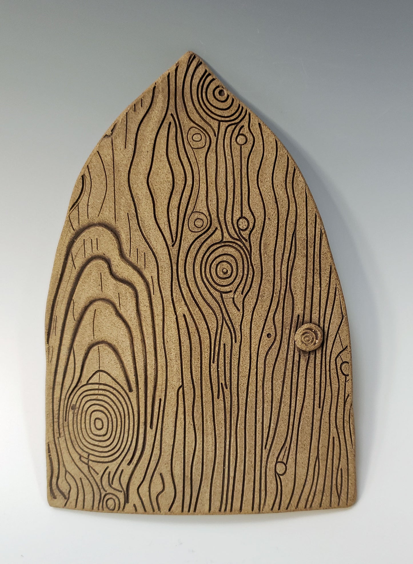 Stoneware fairy door with a textured woodgrain surface on a gray background