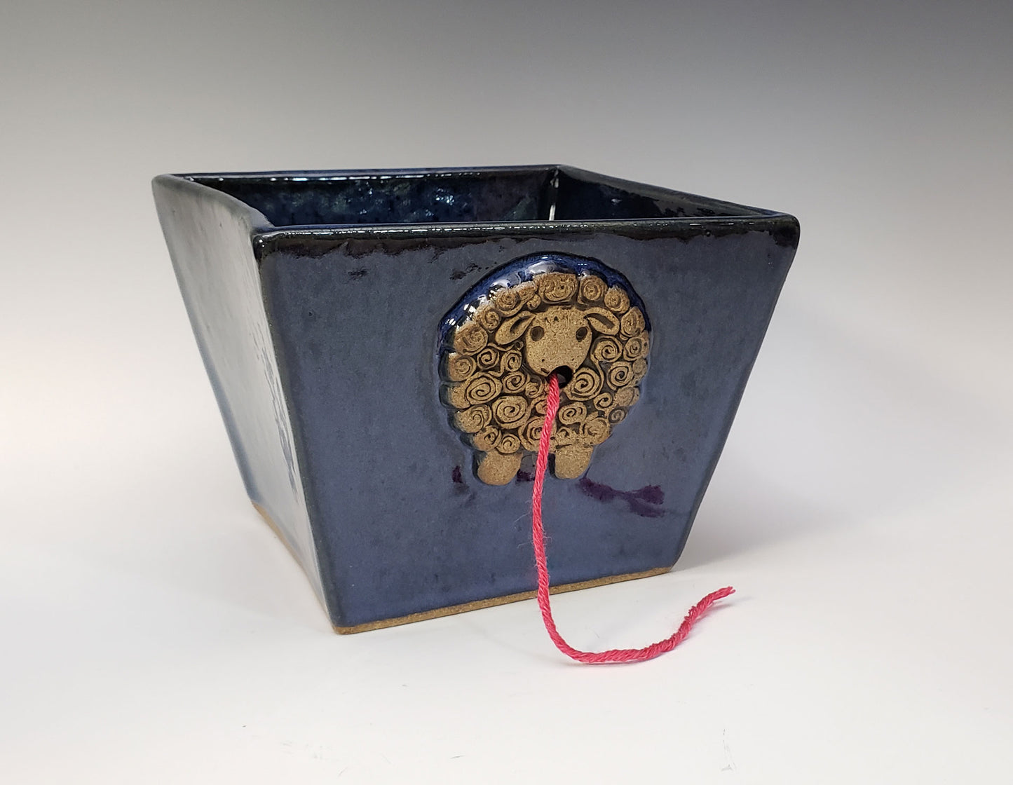 Dark blue stoneware yarn bowl with a decorative sheep design on a white background