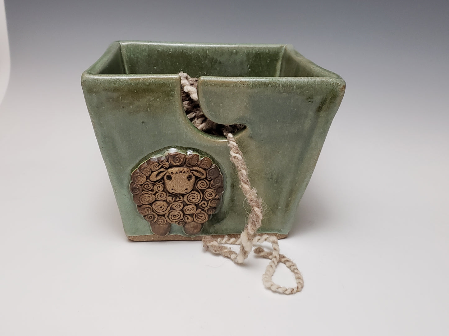 Green stoneware yarn bowl with a decorative sheep design on a white background