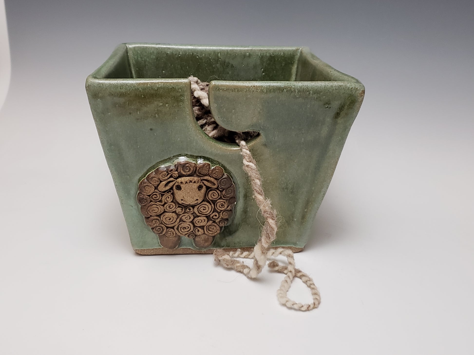 Green stoneware yarn bowl with a decorative sheep design on a white background