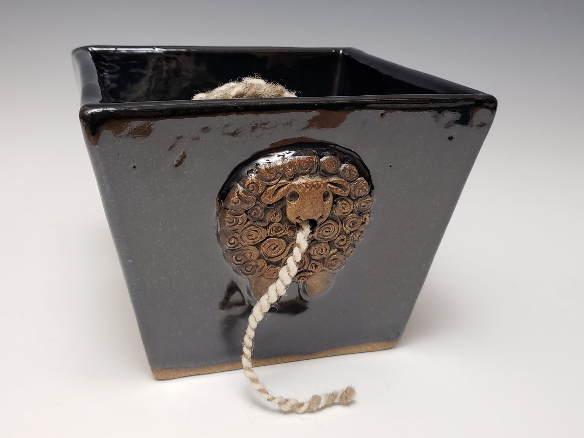Black stoneware yarn bowl with a decorative sheep design on a white background