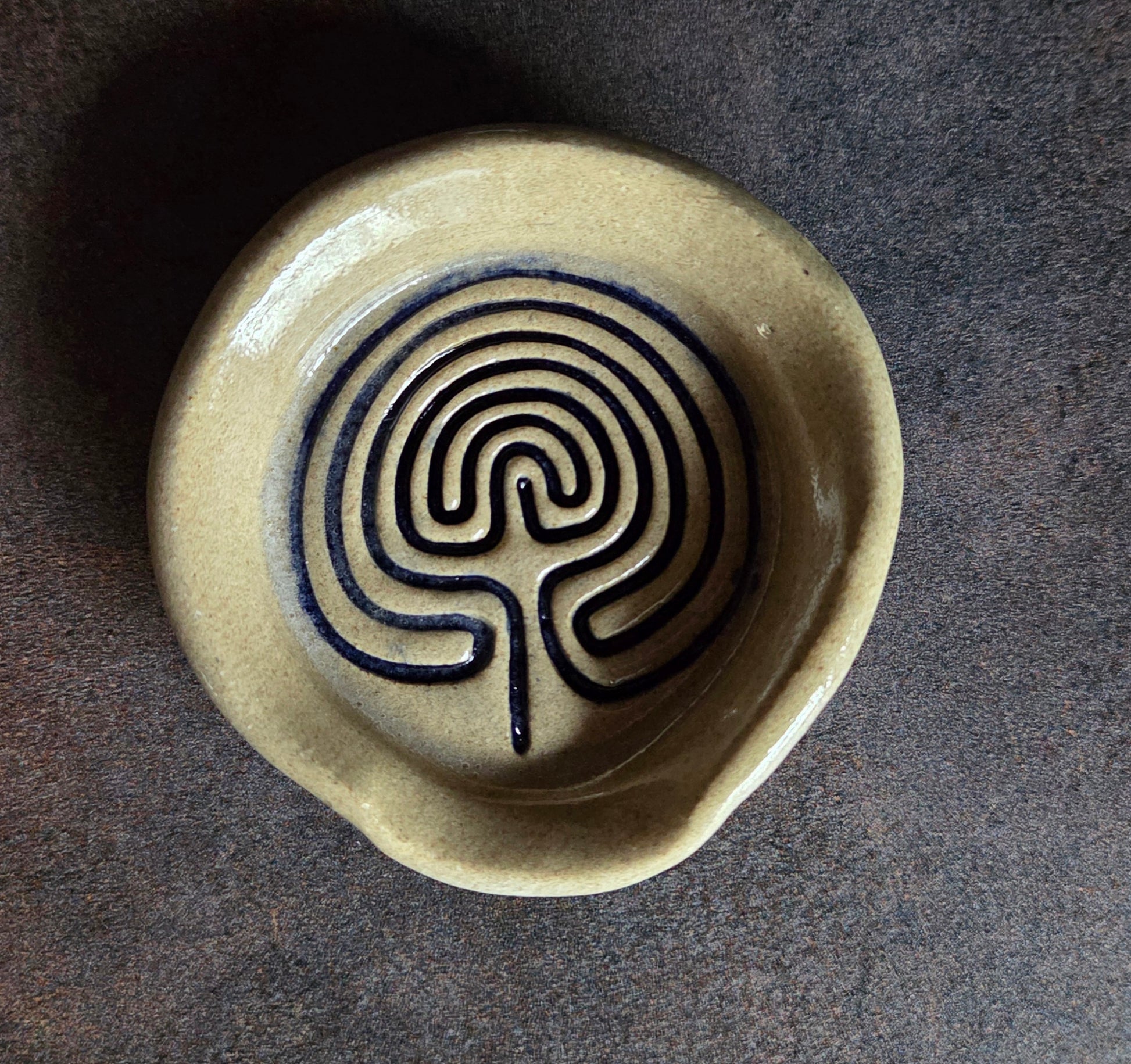 Stoneware teaspoon rest with labyrinth design on a dark surface