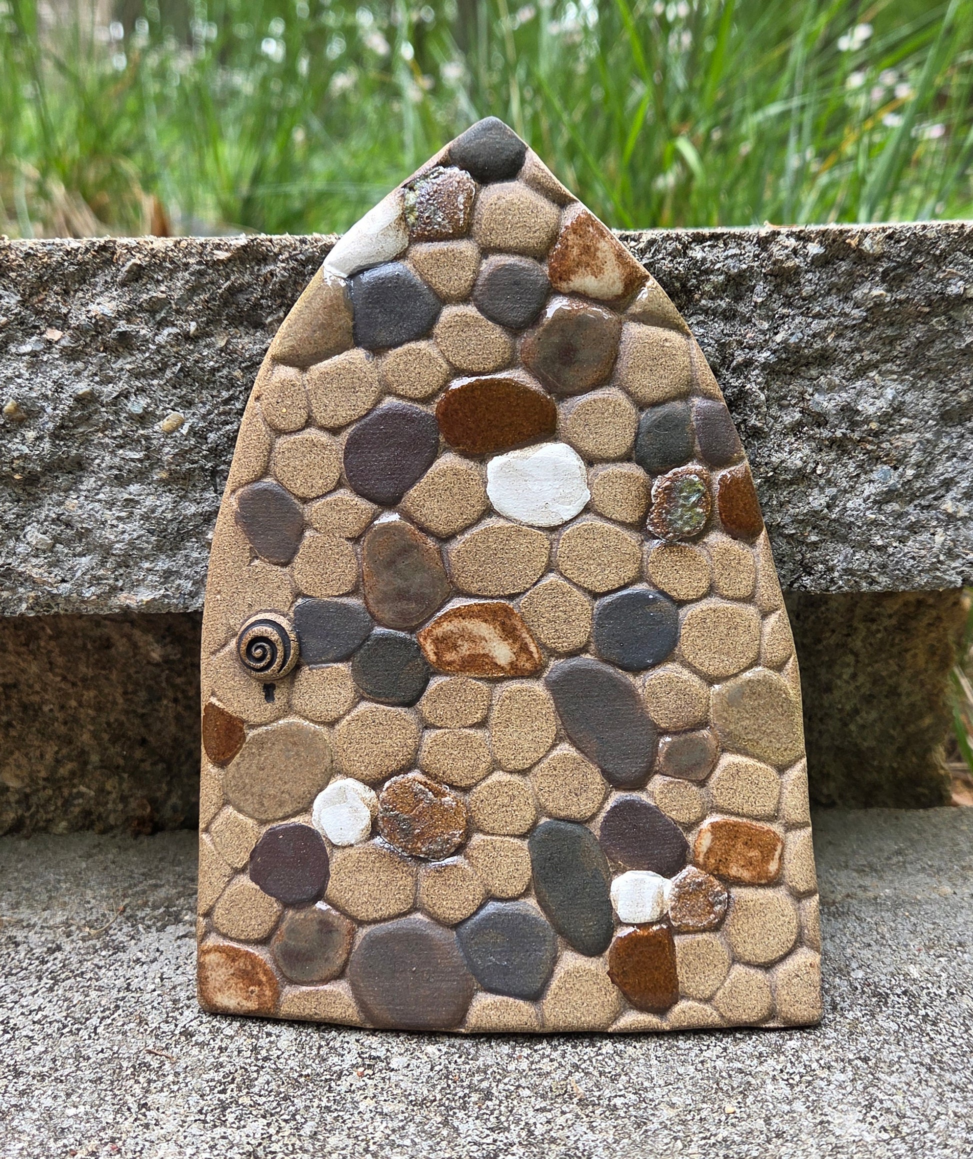 Stoneware fairy door with pebble mosaic design on a natural background