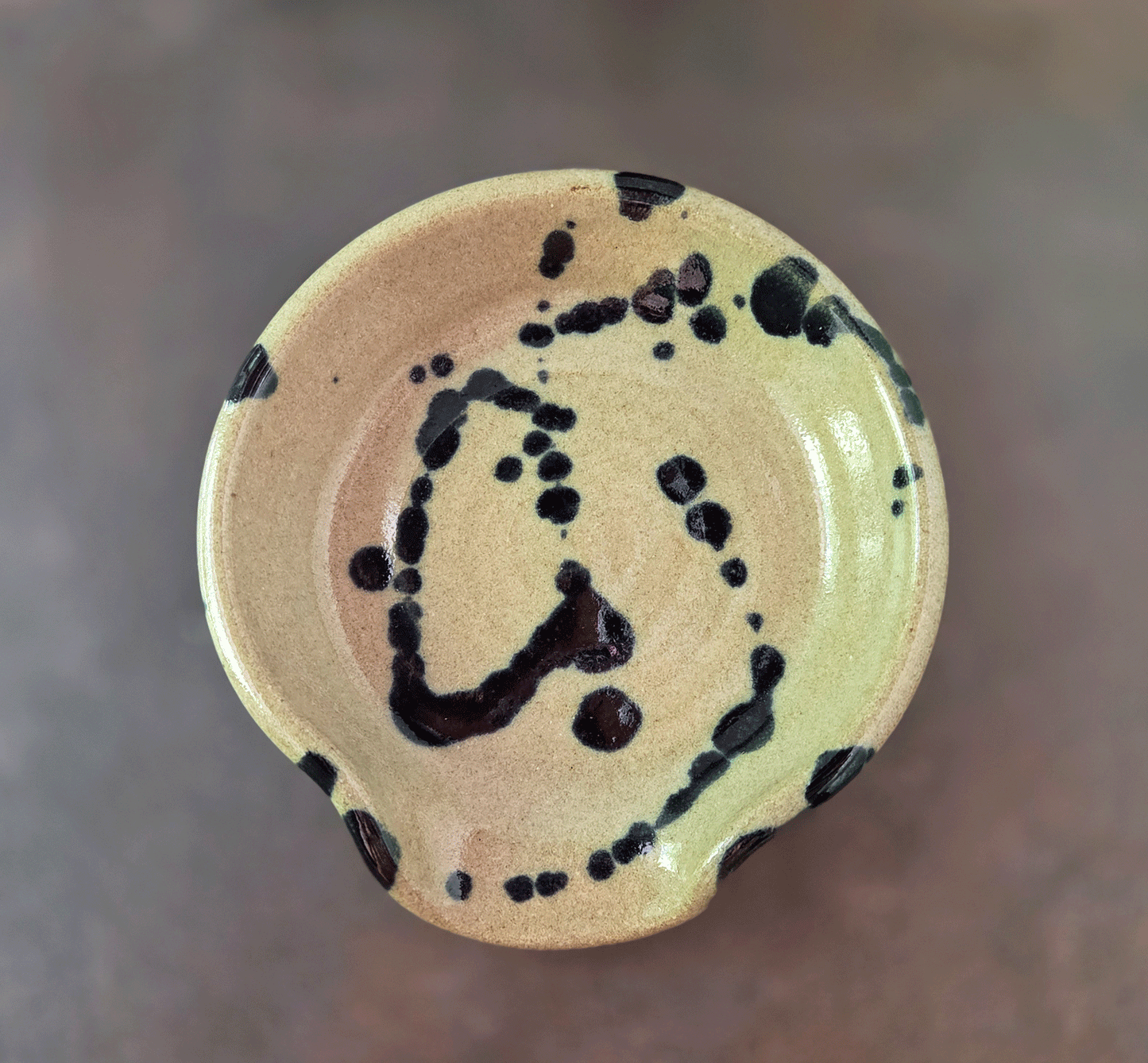 Splatter glaze stoneware spoon rest on a brown background