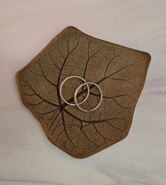 Two silver rings on a leaf-impressed stoneware dish