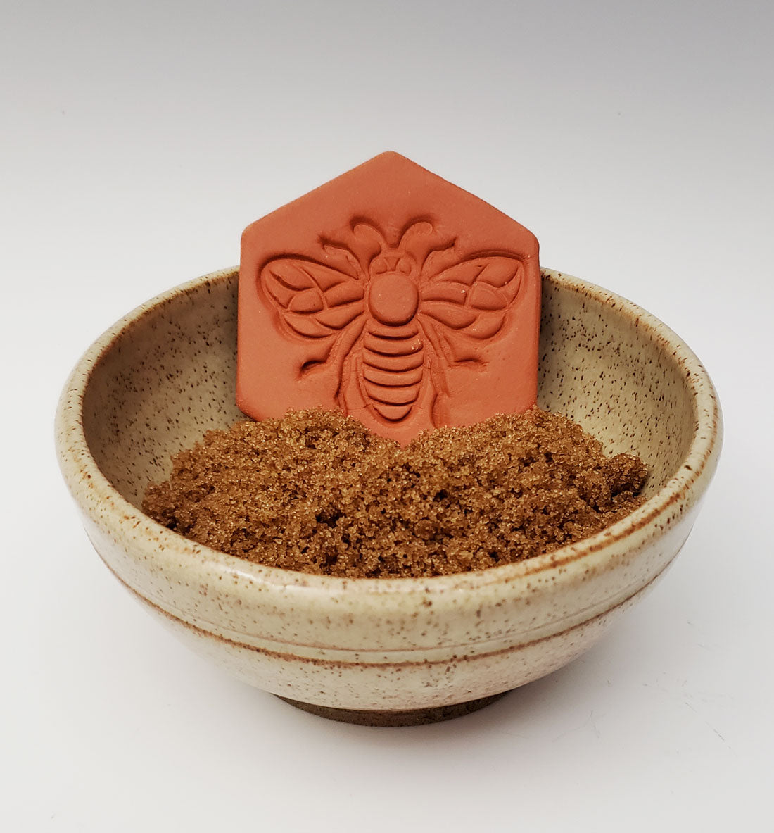 brown sugar keeper with bee design in a bowl of brown sugar