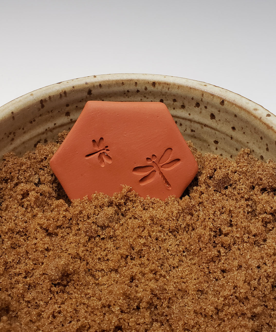 brown sugar keeper with dragonfly design in a bowl of brown sugar