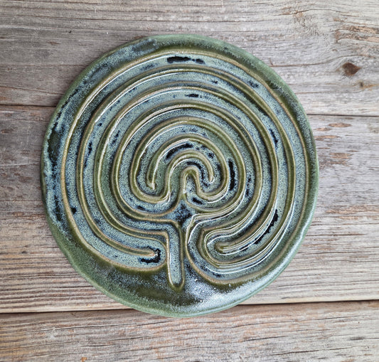 Green ceramic labyrinth on a wooden surface