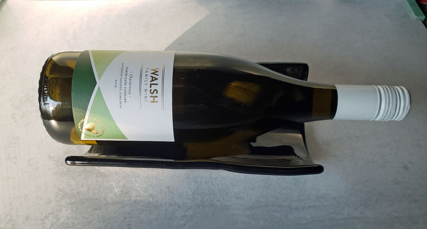 Wine bottle with a label in a black stoneware tray on a gray surface
