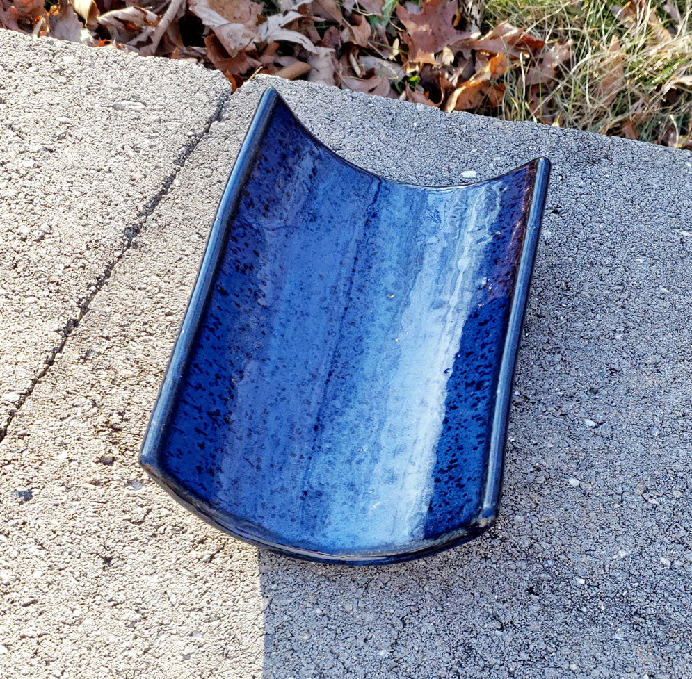 Blue ceramic crescent tray on a concrete surface 