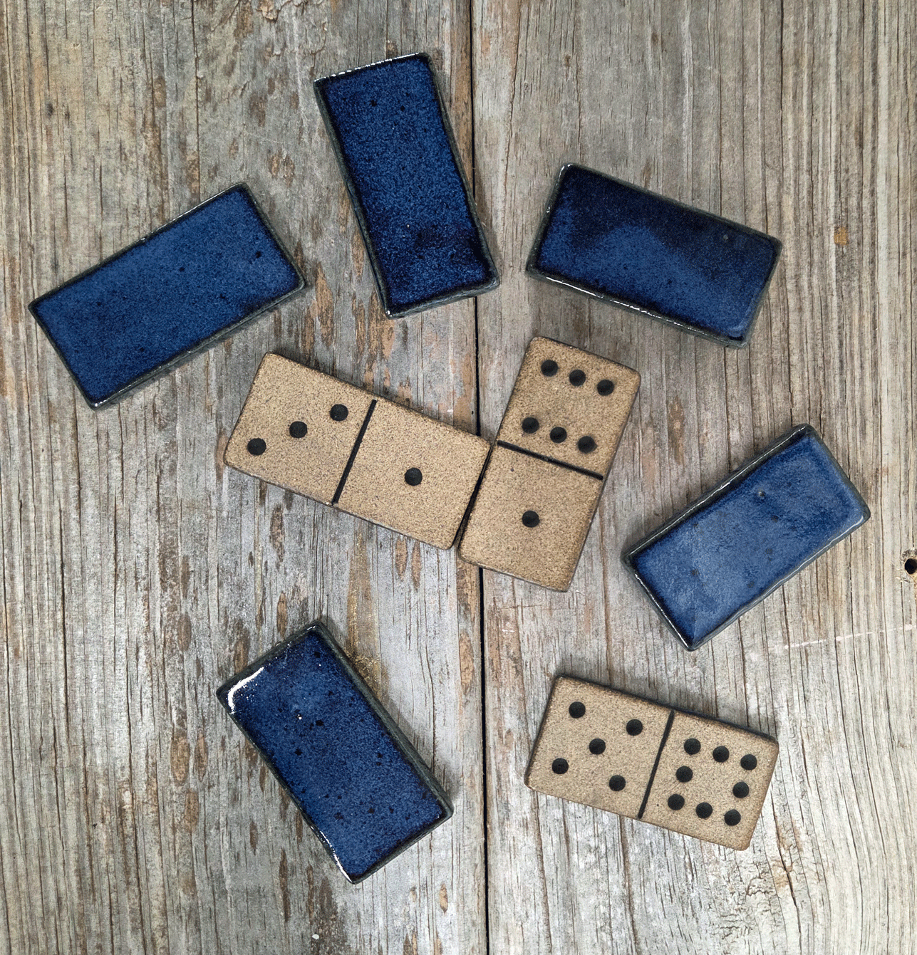 Double-nine domino set in dark blue glaze on a wood surface