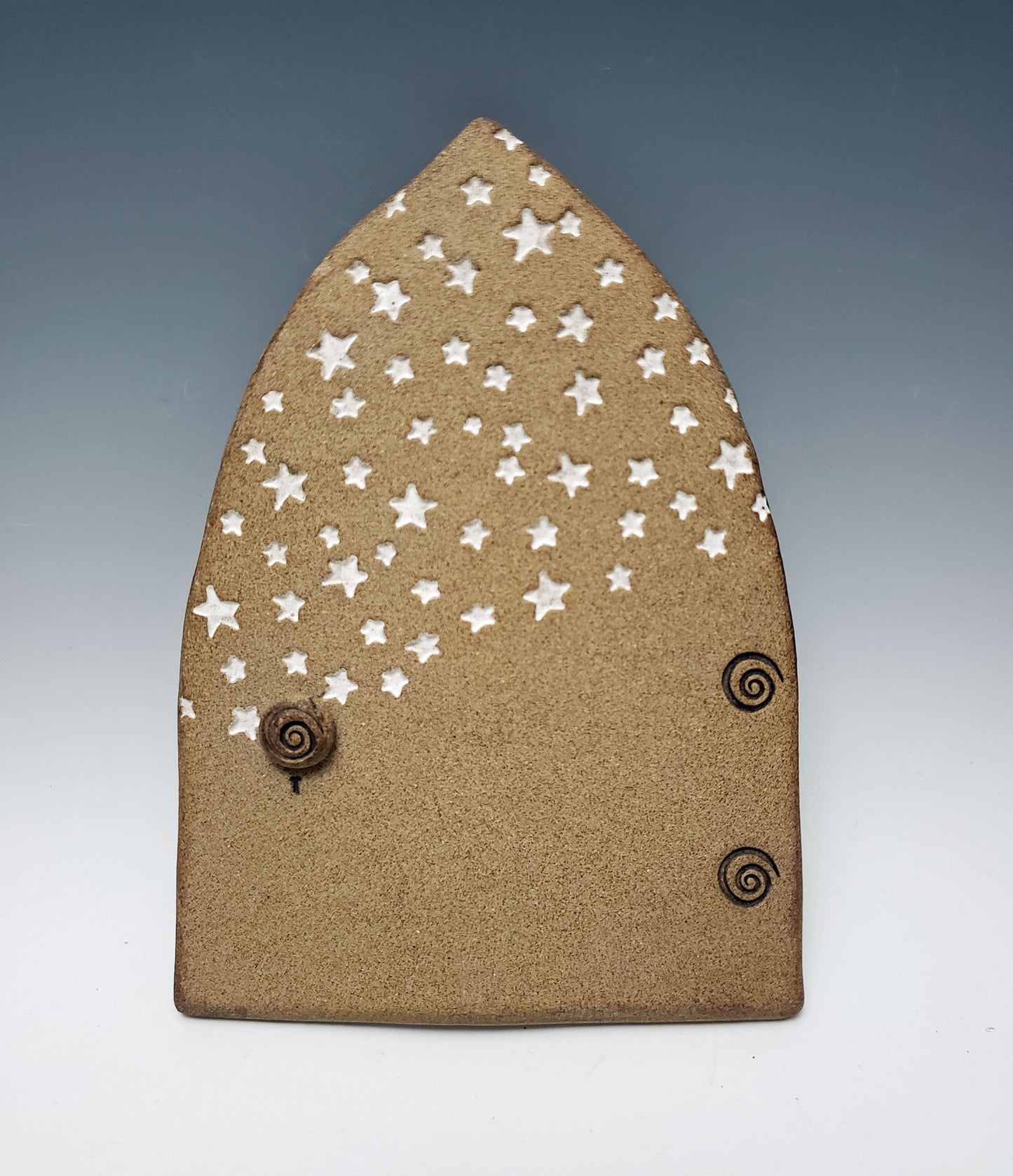 Stoneware fairy door with star design on a gray background