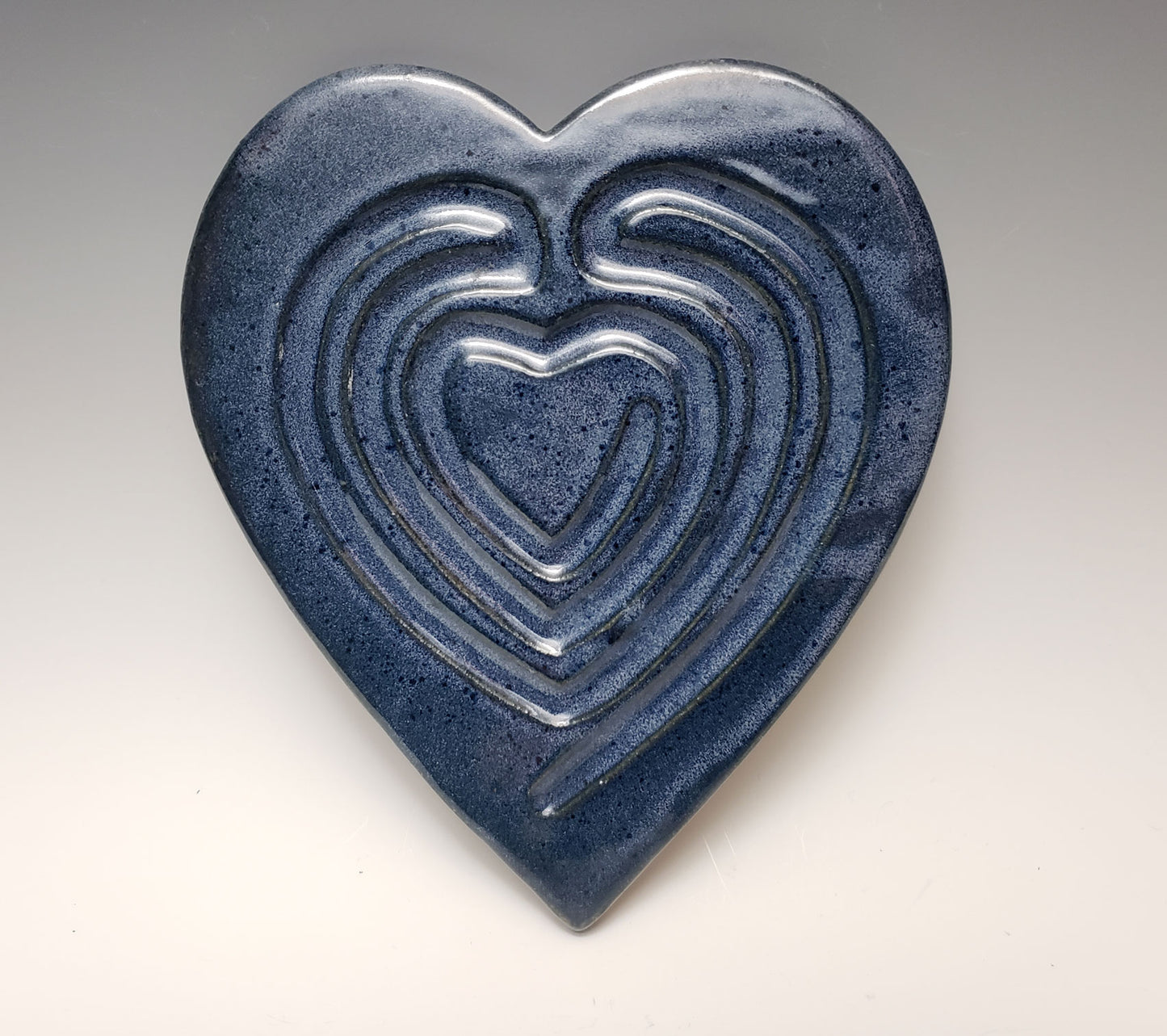 Blue ceramic heart-shaped labyrinth on a gray background