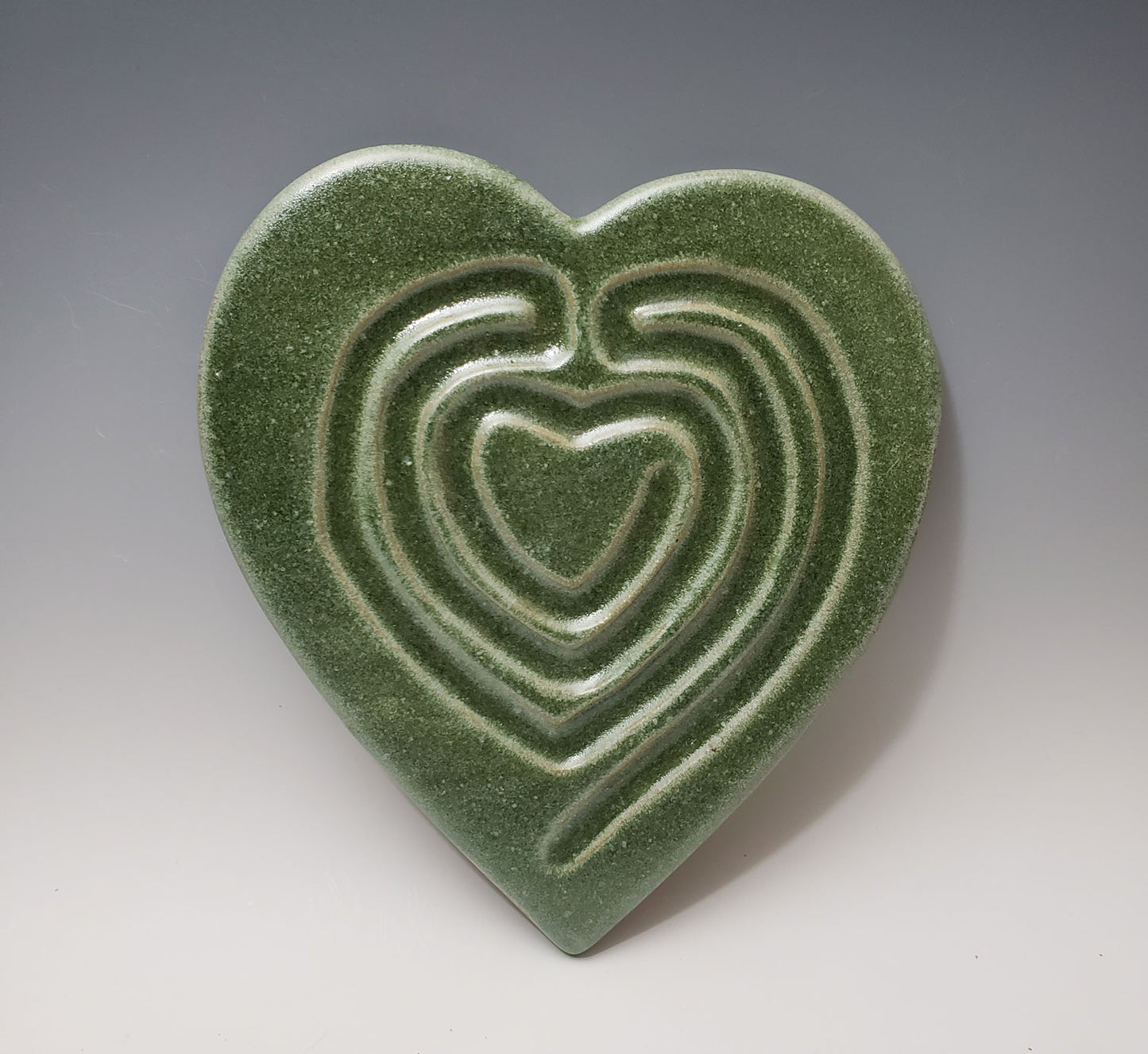 Green ceramic heart labyrinth on a gray background