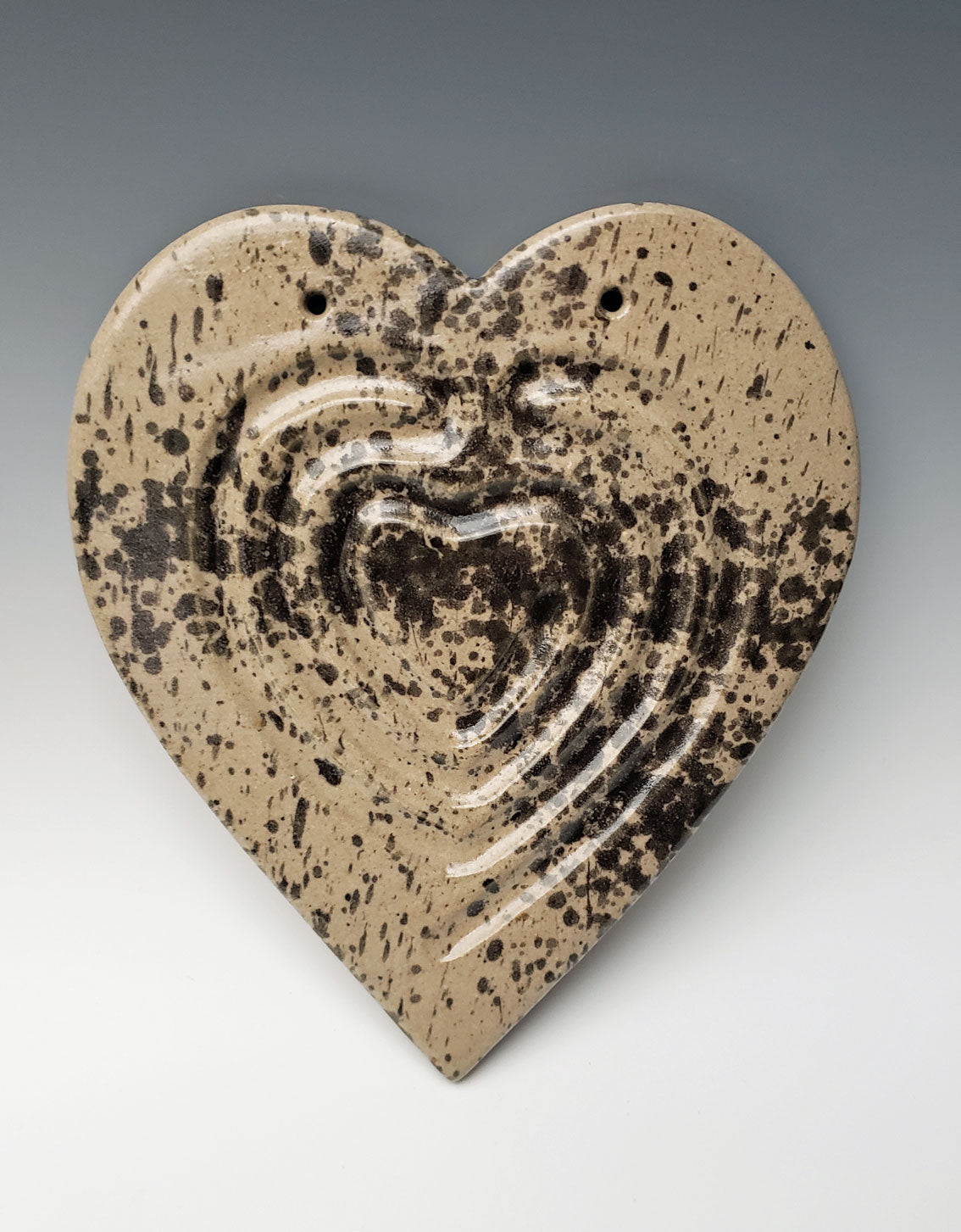 Heart-shaped ceramic labyrinth with speckled design on a gray background