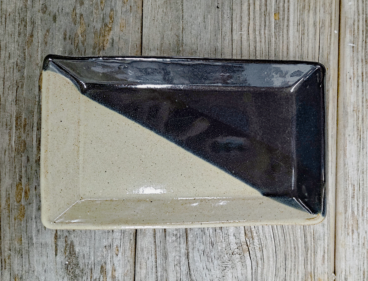 Stoneware side plate in black and eggshell glazes on a wood surface