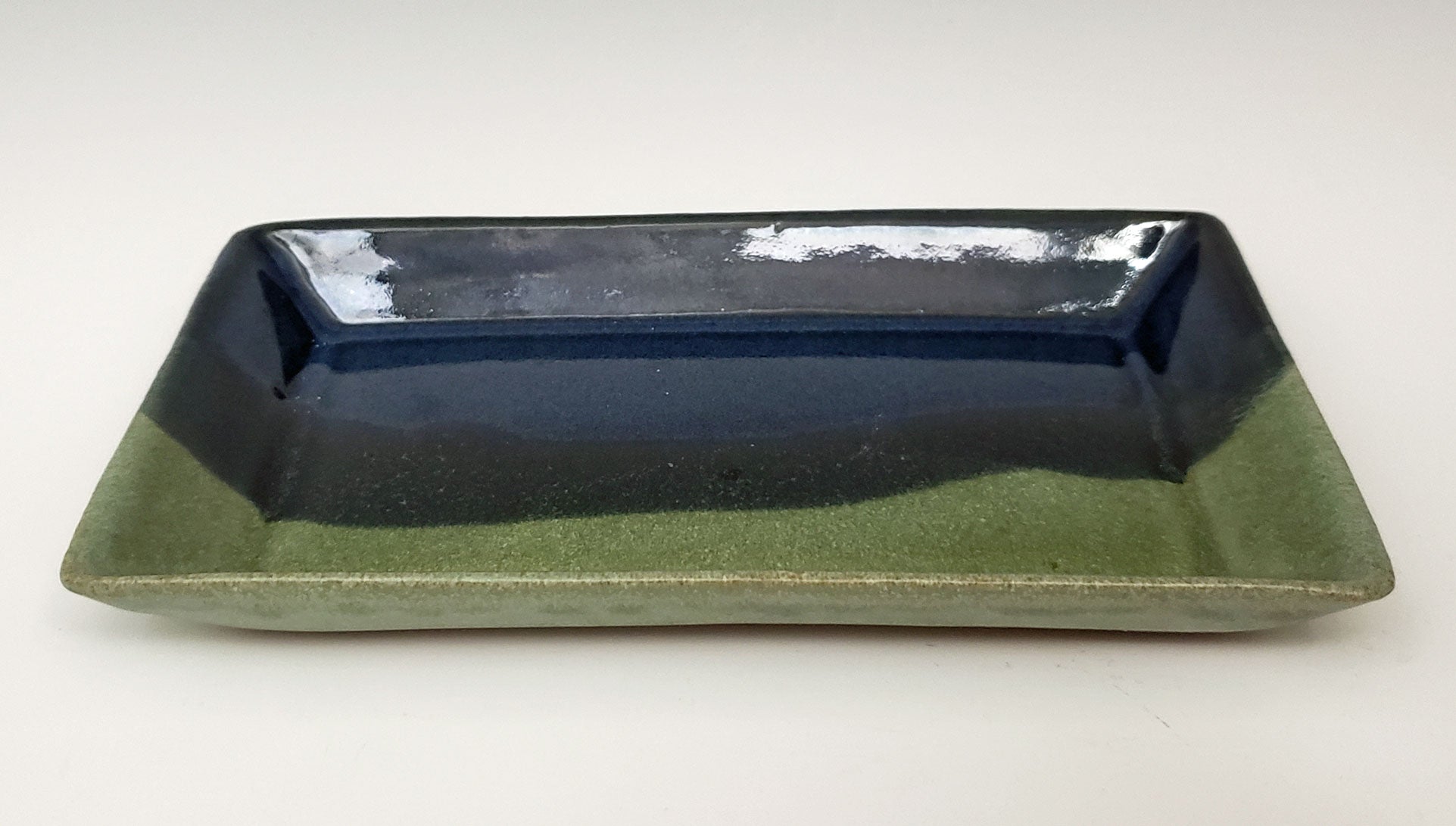 Rectangular stoneware side plate with dark blue & moss glaze on a white background