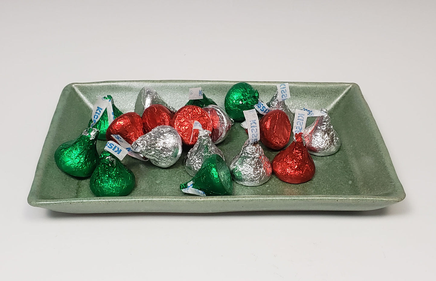 Assorted Hershey's Kisses in green, red, and silver wrappers on a green side plate