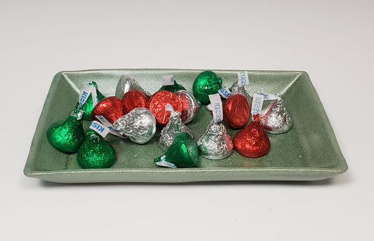 Assorted Hershey's Kisses in green, red, and silver wrappers on a green side plate