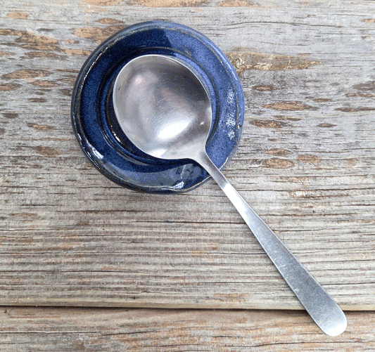 Stoneware tea spoon rest on a wood surface