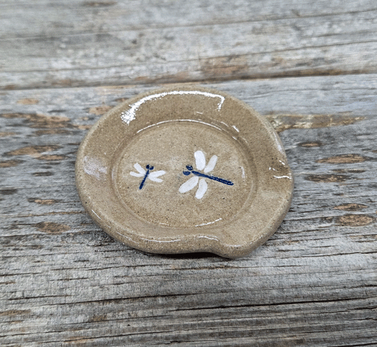 Stoneware teaspoon rest with dragonfly design on a wooden surface