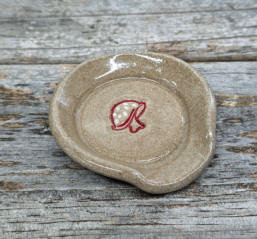 Stoneware teaspoon rest with mushroom design on a wooden surface