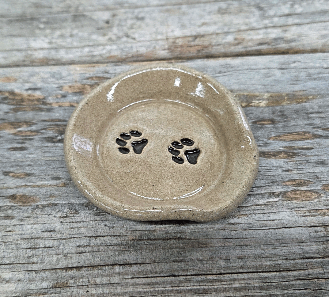 Stoneware teaspoon rest with paw print design on a wooden surface