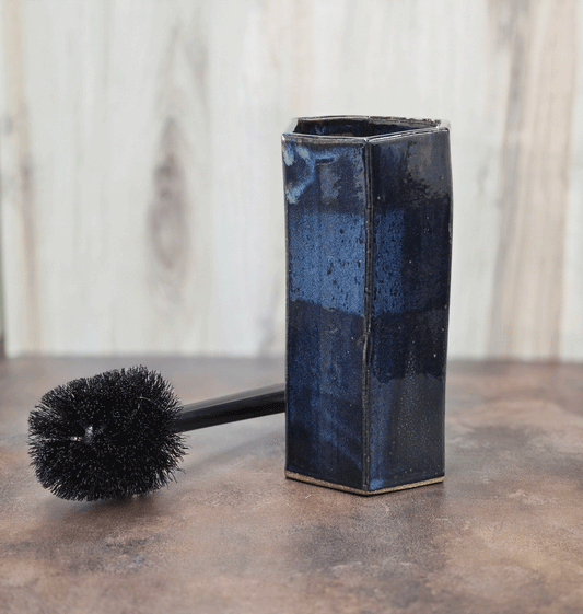 Dark blue toilet brush holder with brush against a neutral background