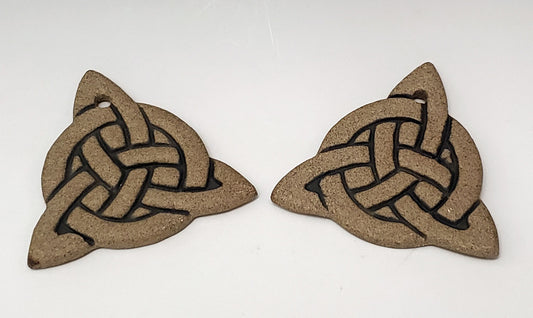 Two triangular stoneware ornaments with Celtic knot design on a white background