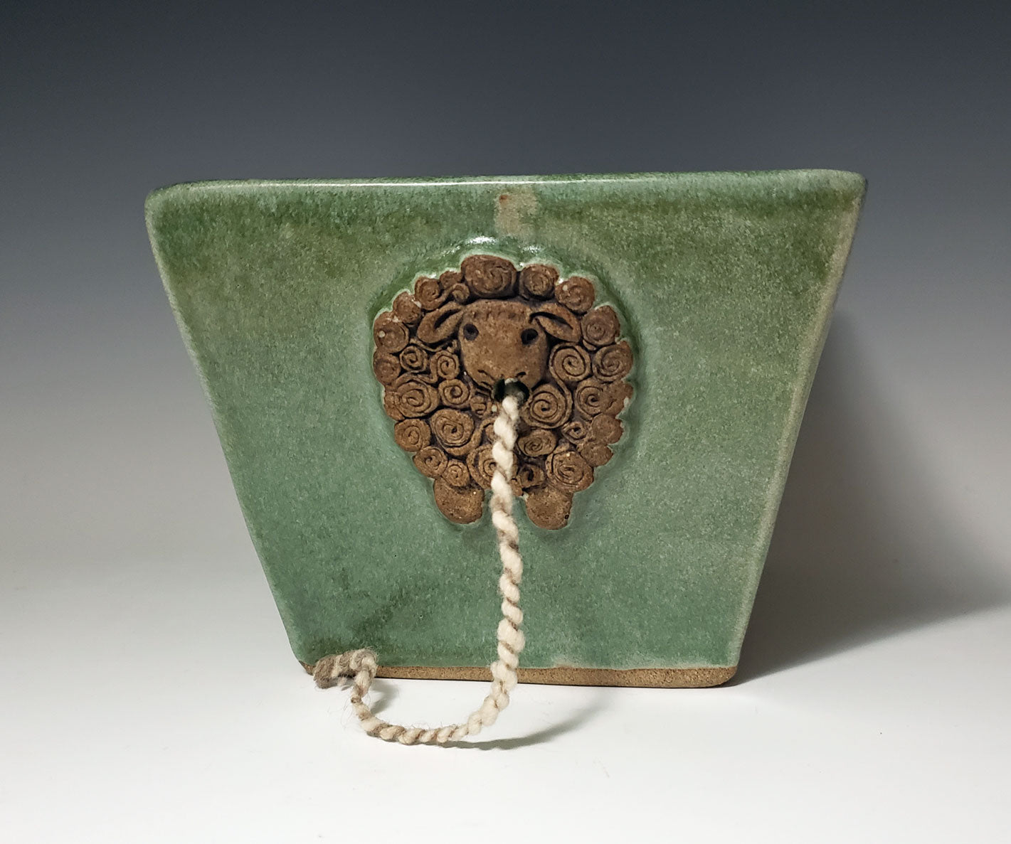 Green stoneware yarn bowl with a decorative sheep design on a white background